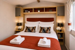 A hotel room with a large bed, two bedside tables with lamps, a red headboard, and a window with curtains. - Sandy Toes New 2026 Stylish 2Bed Steps from Beach (Challaborough)