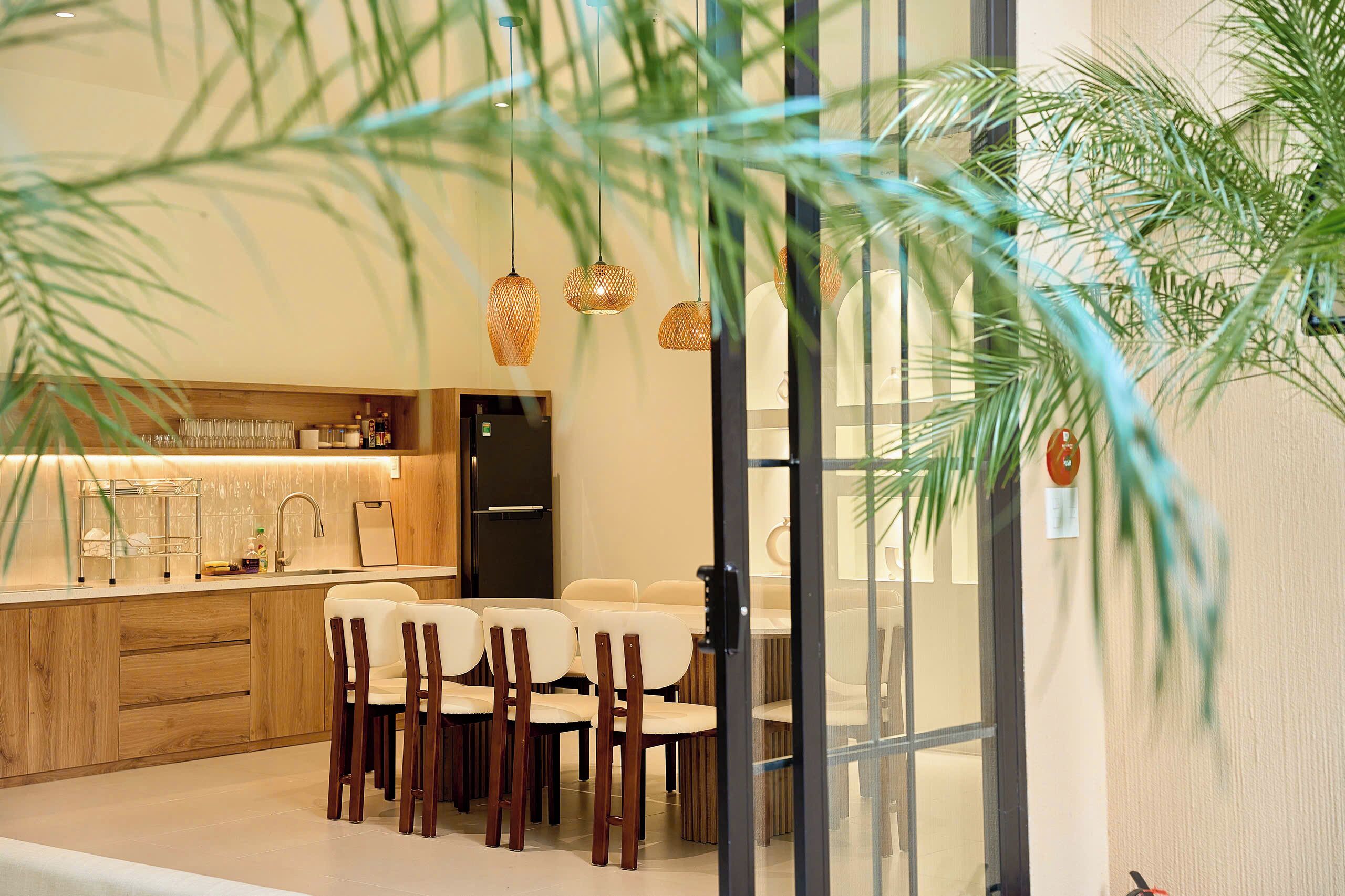 A modern kitchen with wooden cabinets, a built-in oven, and a dining area with a table and chairs.