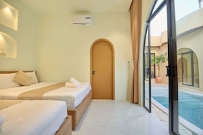 A hotel room with a bed, a door, and a view of a swimming pool. - Mediterranean pool villa near the beach (Thành phố Hồ Chí Minh)
