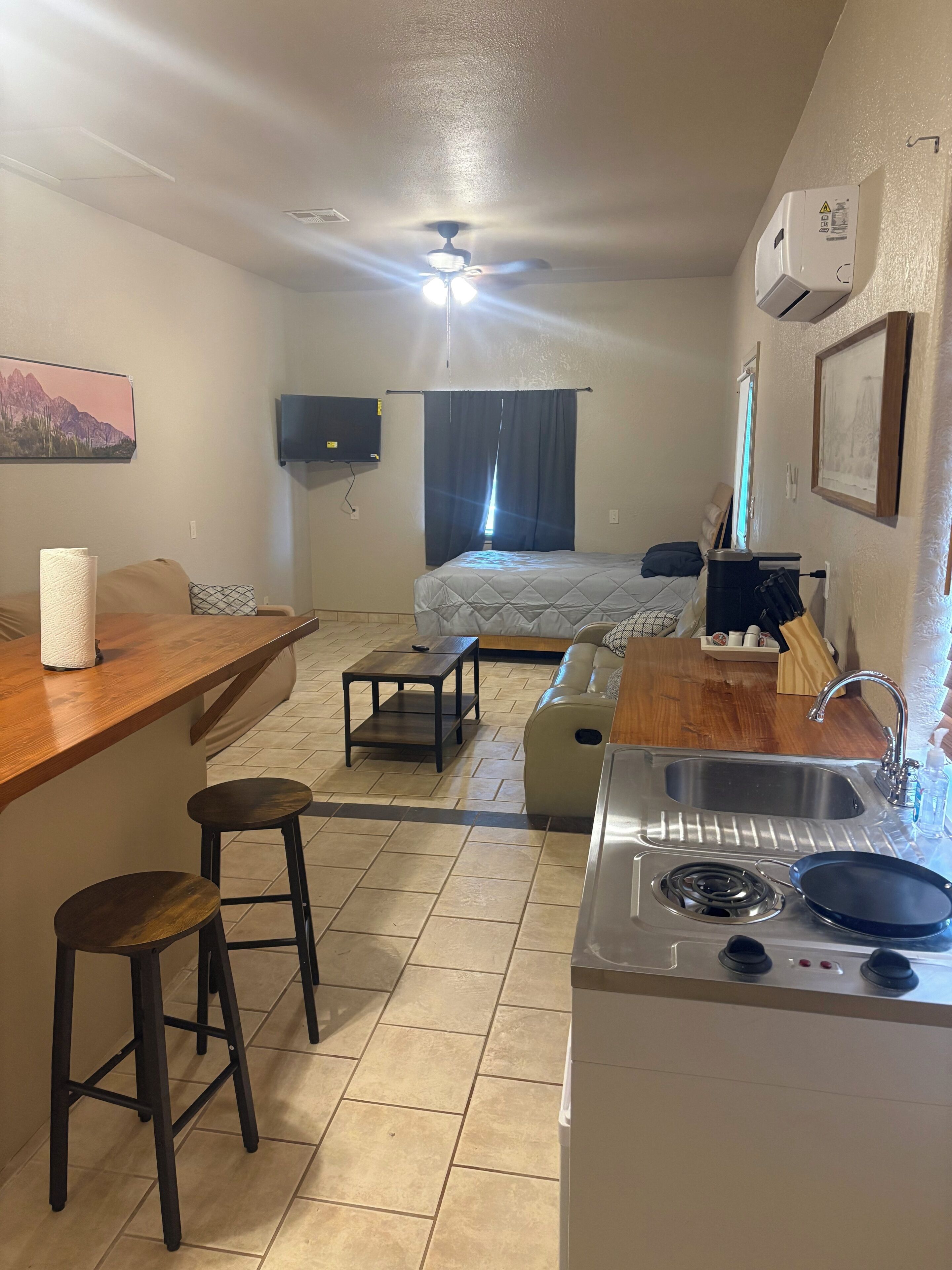 A compact kitchen with a gas stove, sink, and bar area with stools.