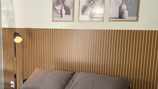 A bedroom with a bed, a bedside lamp, and three framed artworks on the wall. - Estúdio 4 - Vila Granados em Embu das Artes (Embu das Artes)