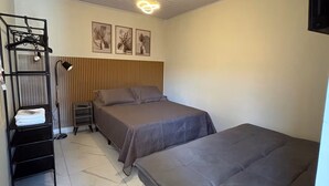 A room with two beds, a hanging light fixture, a wall-mounted TV, and a framed picture. - Estúdio 4 - Vila Granados em Embu das Artes (Embu das Artes)