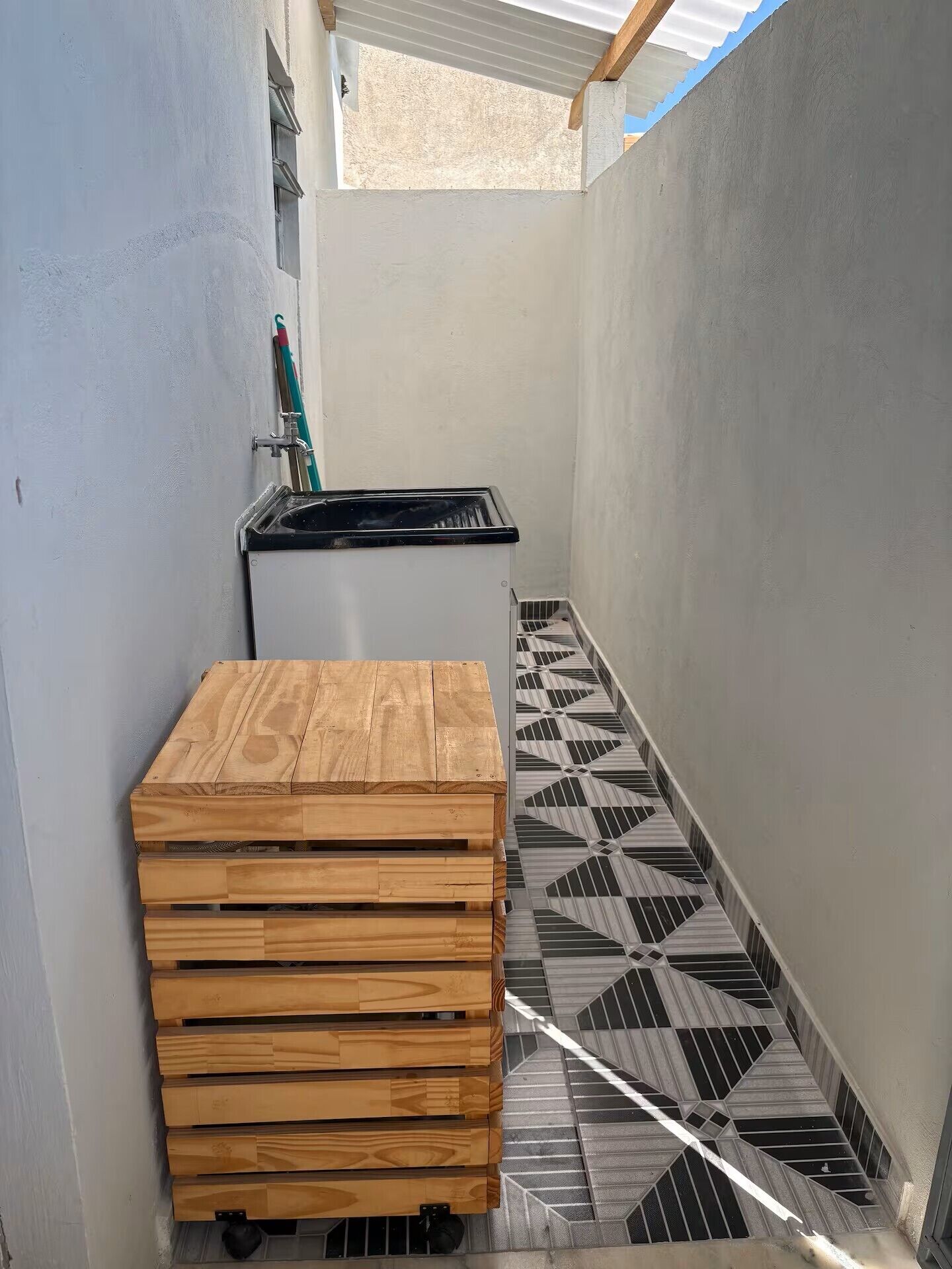 A narrow corridor with a wooden bench, a black stove, and a patterned floor.