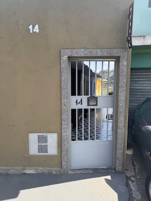 A building entrance with a metal gate, a vent, and a number '14' on the wall.