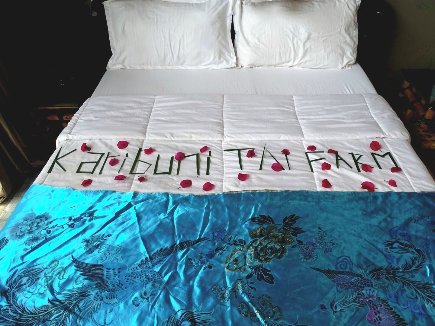 A bed with a white bedspread and a blue embroidered coverlet.