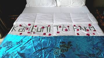 A bed with a white bedspread and a blue embroidered coverlet.