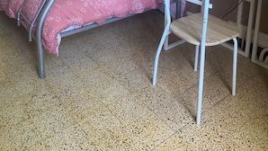 A bunk bed with a pink patterned bedspread, a white chair, a microwave, and a map on the wall. - Vrbo Property (Caudiès-de-Fenouillèdes)