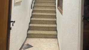 Una escalera con barandilla, una puerta a la izquierda y una ventana a la derecha.