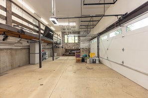 A spacious garage with high ceilings, exposed beams, and a concrete floor. - New 5 Bedroom Luxury Mountain Retreat w/Hot Tub, Private Wooded Lot - Sleeps 8 (Silverthorne)