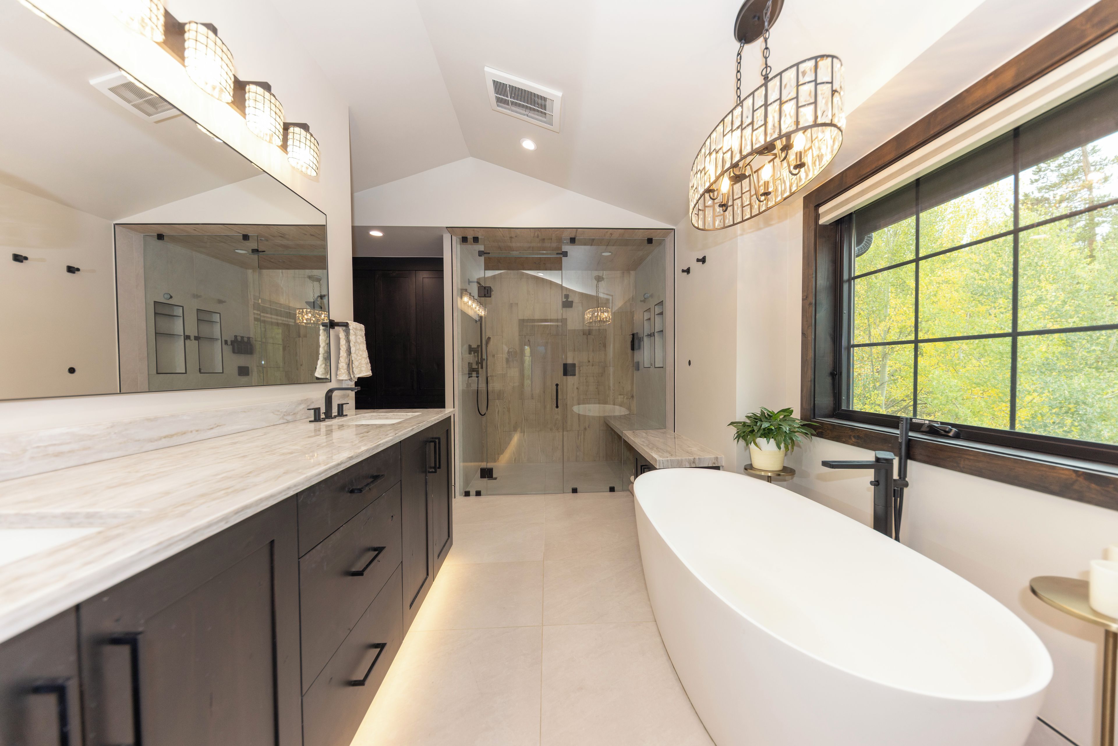 A modern bathroom with a large bathtub, a glass-enclosed shower, and a vanity with a mirror.