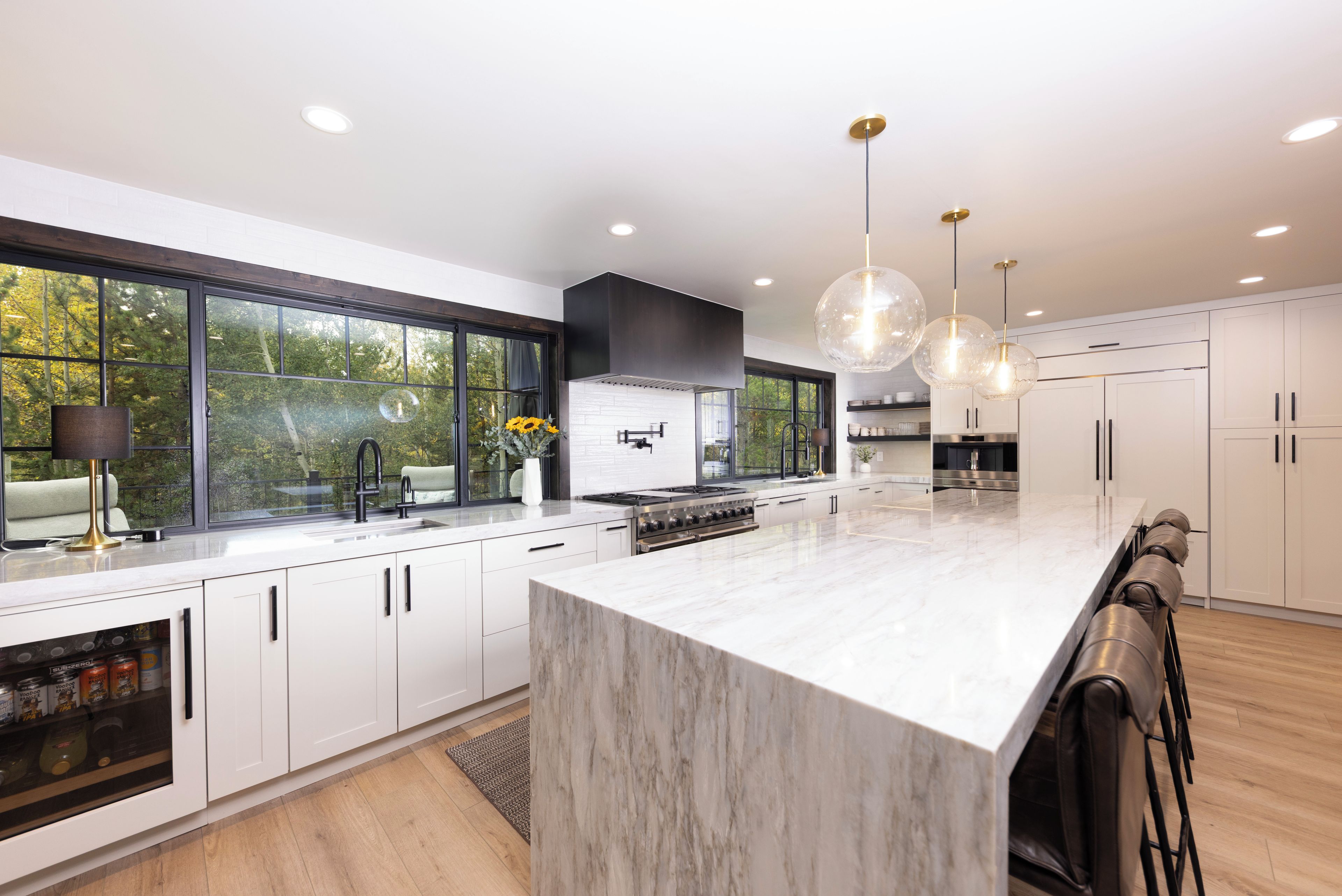 A modern kitchen with white cabinetry, a large island, and pendant lighting.
