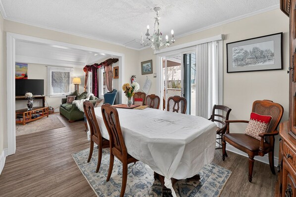A dining room with a large table, chairs, and a chandelier.