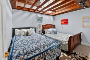 A bedroom with two beds, a skylight, and artwork on the walls.