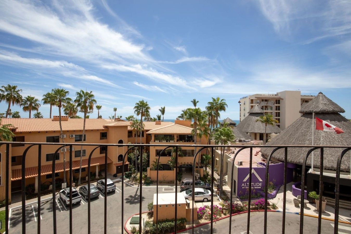 A hotel with multiple buildings, a parking lot, and a view of the ocean.