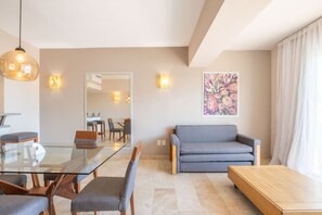 A modern living room with a glass dining table, grey sofa, and a wooden coffee table. - Depto. a 5 min del mar y el centro de San Jose 106 (San José del Cabo)