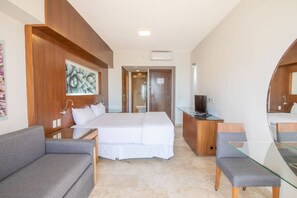 A hotel room with a bed, a sofa, a desk with a TV, and a bathroom visible through an open door. - Estudio a 5 min de la playa en San José del Cabo (San José del Cabo)