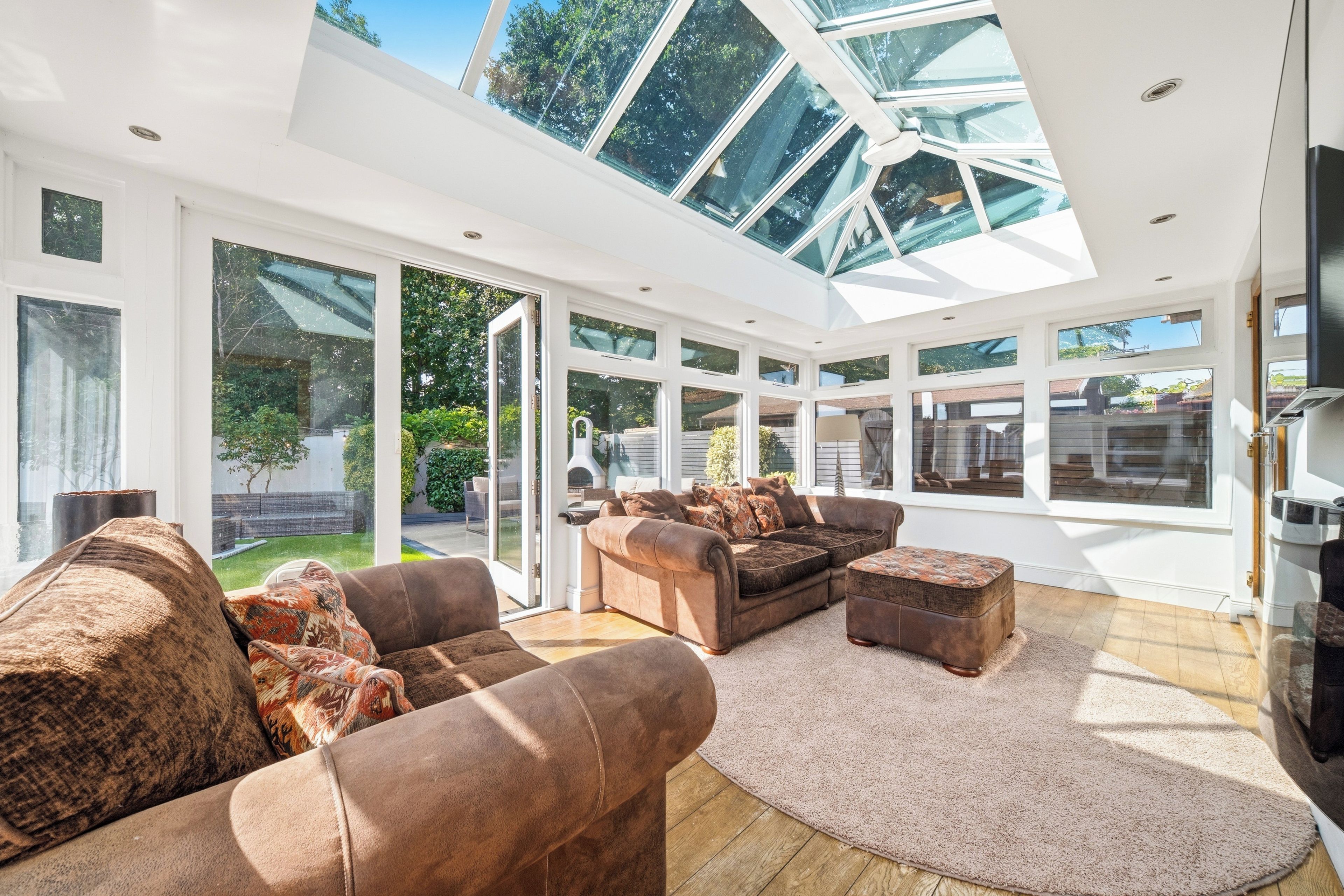 A spacious living room with a high ceiling and large windows, featuring a sectional sofa, a coffee table, and a fireplace.