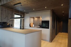 A modern kitchen with a central island, wooden ceiling, and built-in appliances.