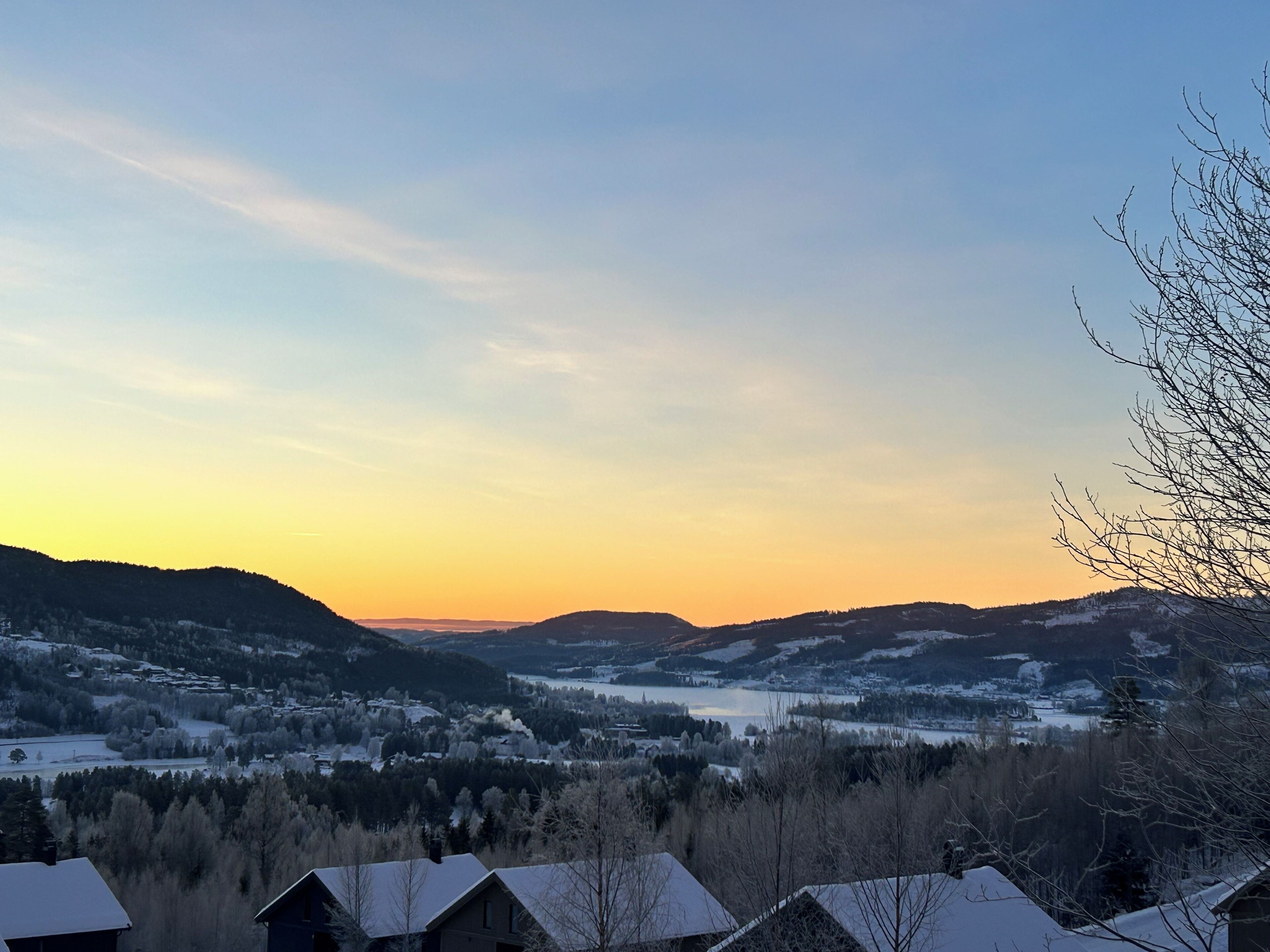 En vy över en dal med snötäckta kullar och en sjö.