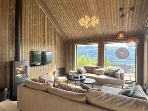 Una sala de estar moderna con un ventanal grande, una chimenea y un televisor.