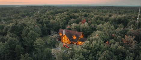 Une grande cabane en rondins, entourée d’une forêt dense, offrant une vue dégagée sur le paysage environnant.