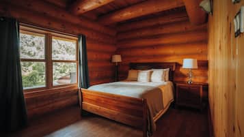 Une chambre à coucher dans une cabane en bois, avec un lit à baldaquin, deux lampes de chevet et une fenêtre avec des rideaux.