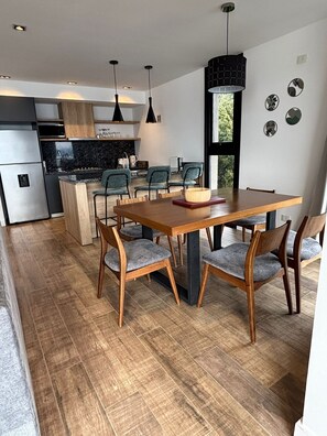 Een moderne keuken met een centraal eiland, houten stoelen en een eettafel.