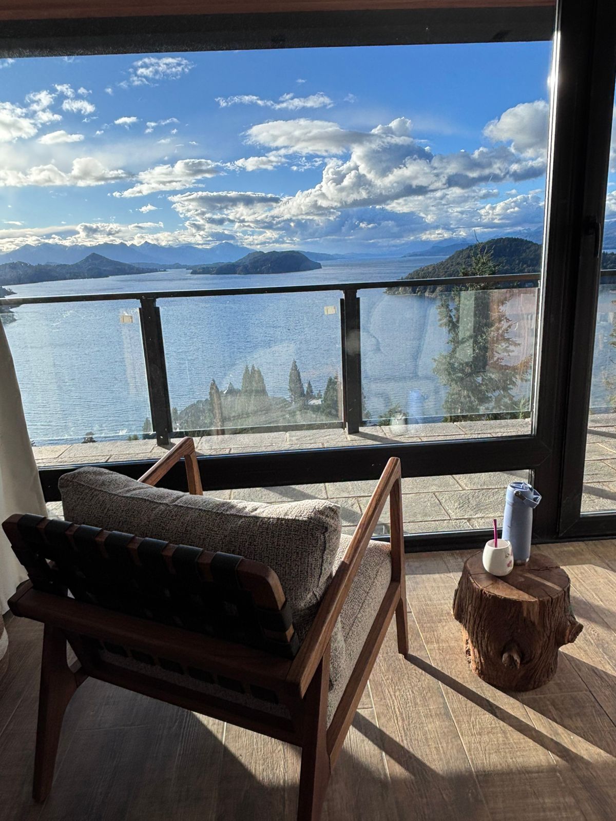 A room with a wooden bench and a small table with a cup and a bottle.