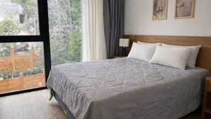 Un dormitorio con una cama grande, una mesita de noche, una lámpara y dos cuadros en la pared.