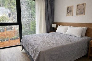 Une chambre à coucher avec un grand lit, une table de chevet, une lampe et deux tableaux encadrés accrochés au mur.