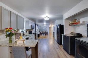 A modern kitchen with a central island, a dining area, and a laundry area. - Ultimate Pocono Getaway  HotTub•Theater•GameRoom (Tunkhannock Township)