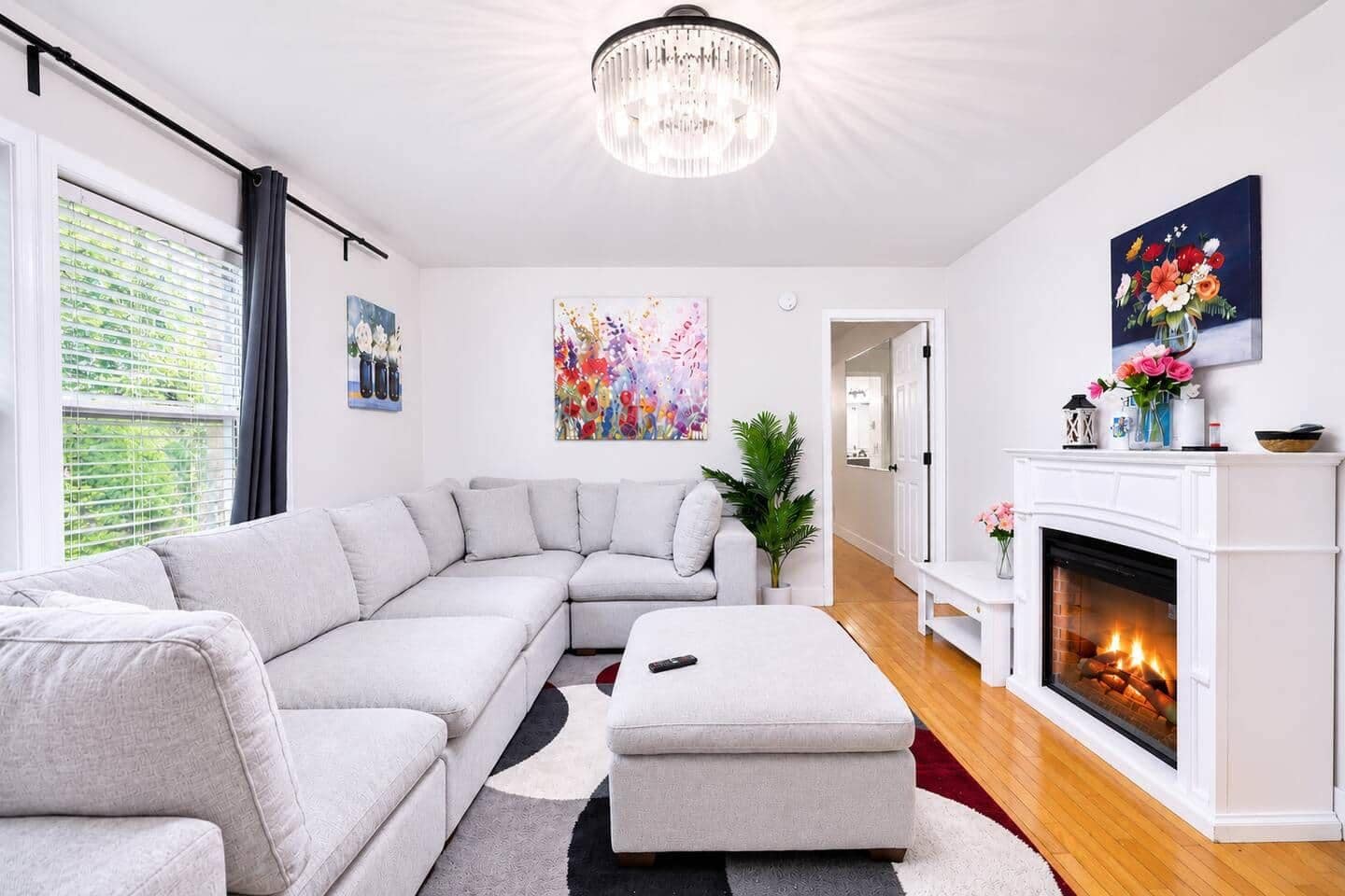 A modern living room with a sectional sofa, a fireplace, and artwork on the walls.