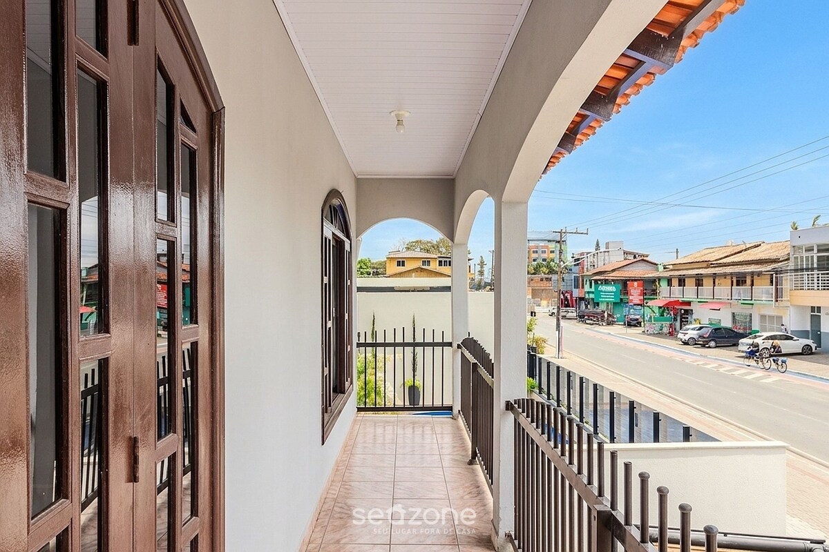 Ein Balkon mit Blick auf eine Straße, ein Fliesenboden und ein Geländer.