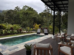 A pool area with a wooden deck, lounge chairs, and a covered seating area. - Villa Azur 1 - New 3-bedroom with Arenal views, pool, rainforest in La Fortuna (La Fortuna)