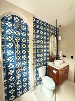 Een badkamer met een douche, toilet en wastafel met spiegel.