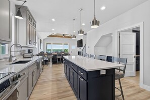 A modern kitchen with a central island, built-in appliances, and pendant lighting. - Ellison Bay 3BR Vacation Home - Water Views, Beach & Boat Parking (Ellison Bay)