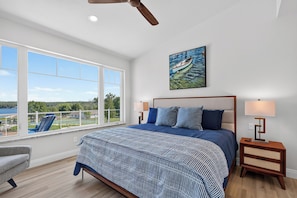 A bedroom with a large bed, a view of the outdoors, and a ceiling fan. - Ellison Bay 3BR Vacation Home - Water Views, Beach & Boat Parking (Ellison Bay)