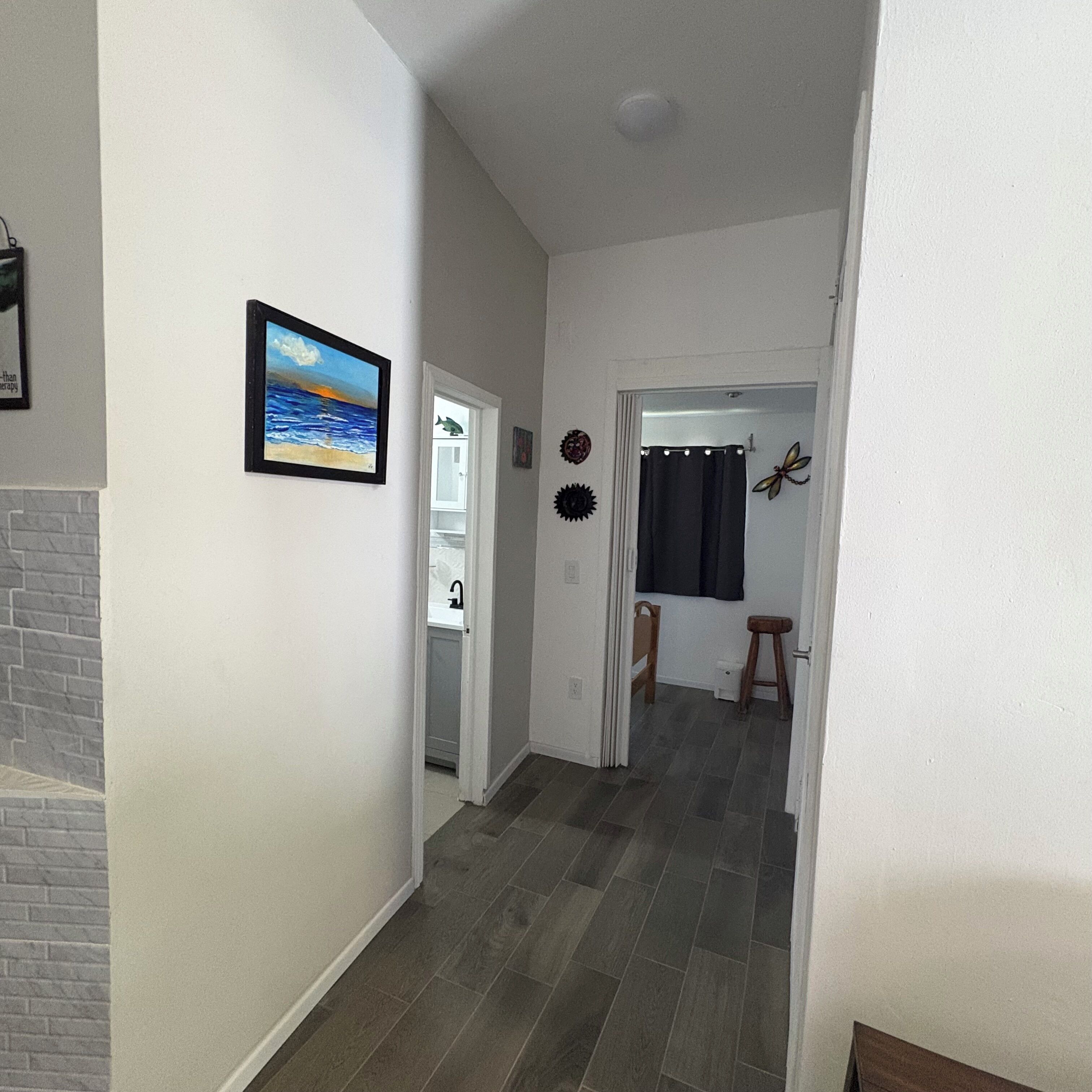 A hallway with a fireplace, a door leading to a bathroom, and a dining area with a chair and stool.