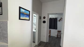 A hallway with a fireplace, a door leading to a bathroom, and a dining area with a chair and stool.