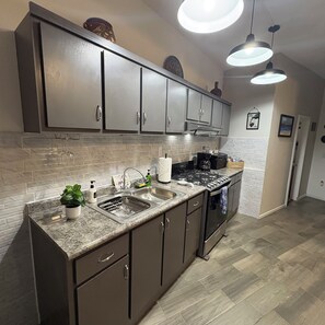 A modern kitchen with granite countertops, stainless steel appliances, and a backsplash. - CasitaRosarito Parking & Quick Highway access (playas de Rosarito)