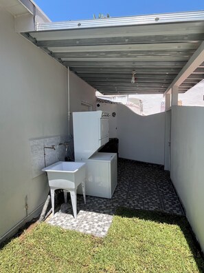 A small, enclosed outdoor area with a white washing station, a small table, and a tiled floor. - CasitaRosarito Parking & Quick Highway access (playas de Rosarito)