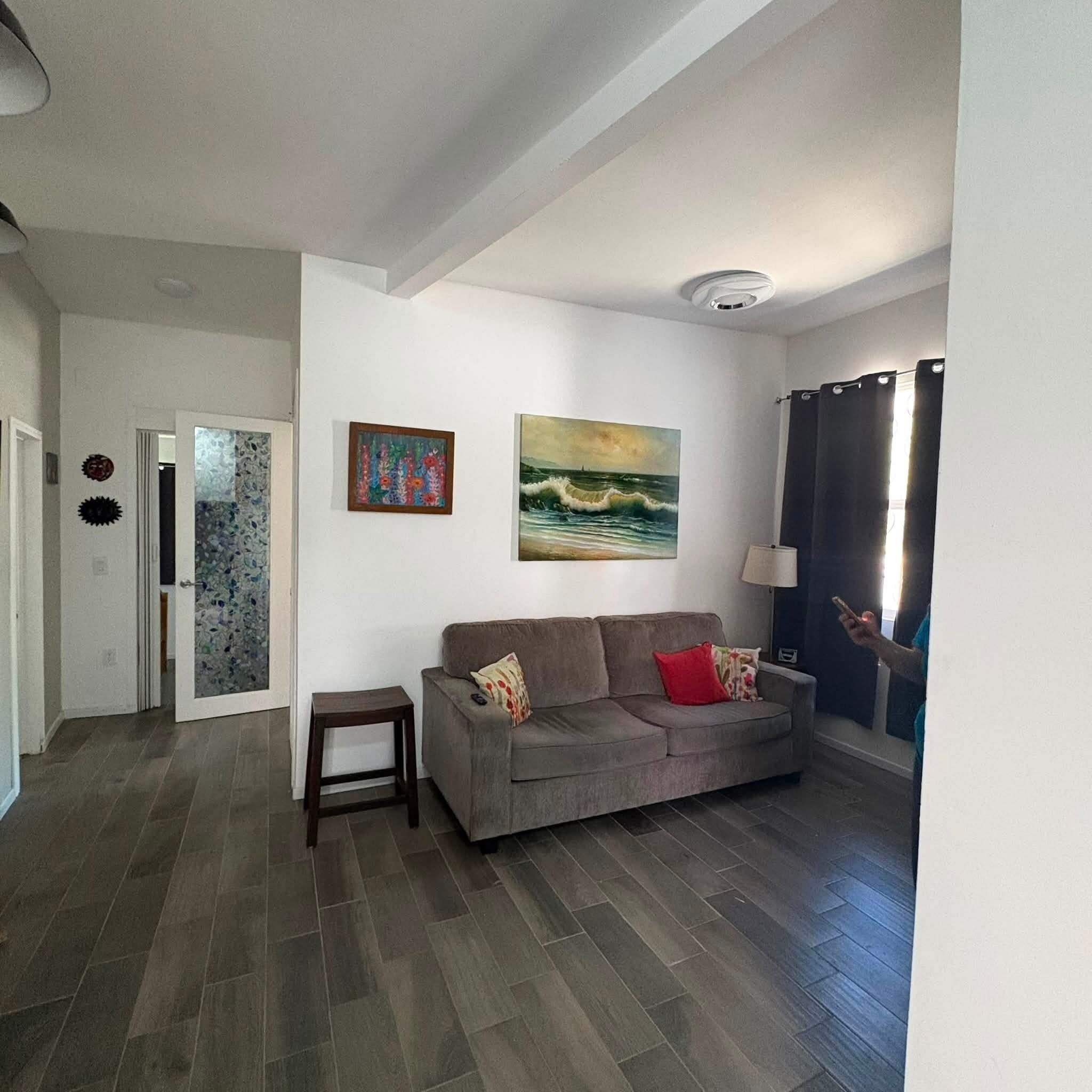 A living room with a grey sofa, a small table, and two paintings on the wall.