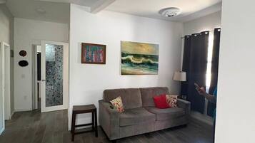 A living room with a grey sofa, a small table, and two paintings on the wall.