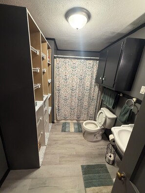 Une petite salle de bain comprenant des toilettes, un lavabo et des placards de rangement.