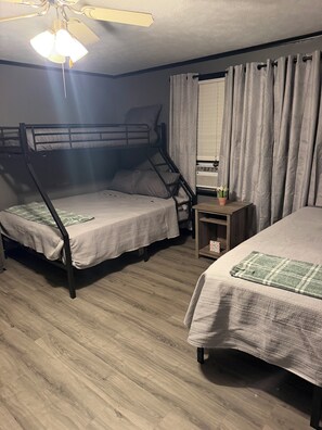 A room with two bunk beds, a ceiling fan, a small table with a potted plant, and a window with curtains. - The Willow at Toomsuba (Toomsuba)