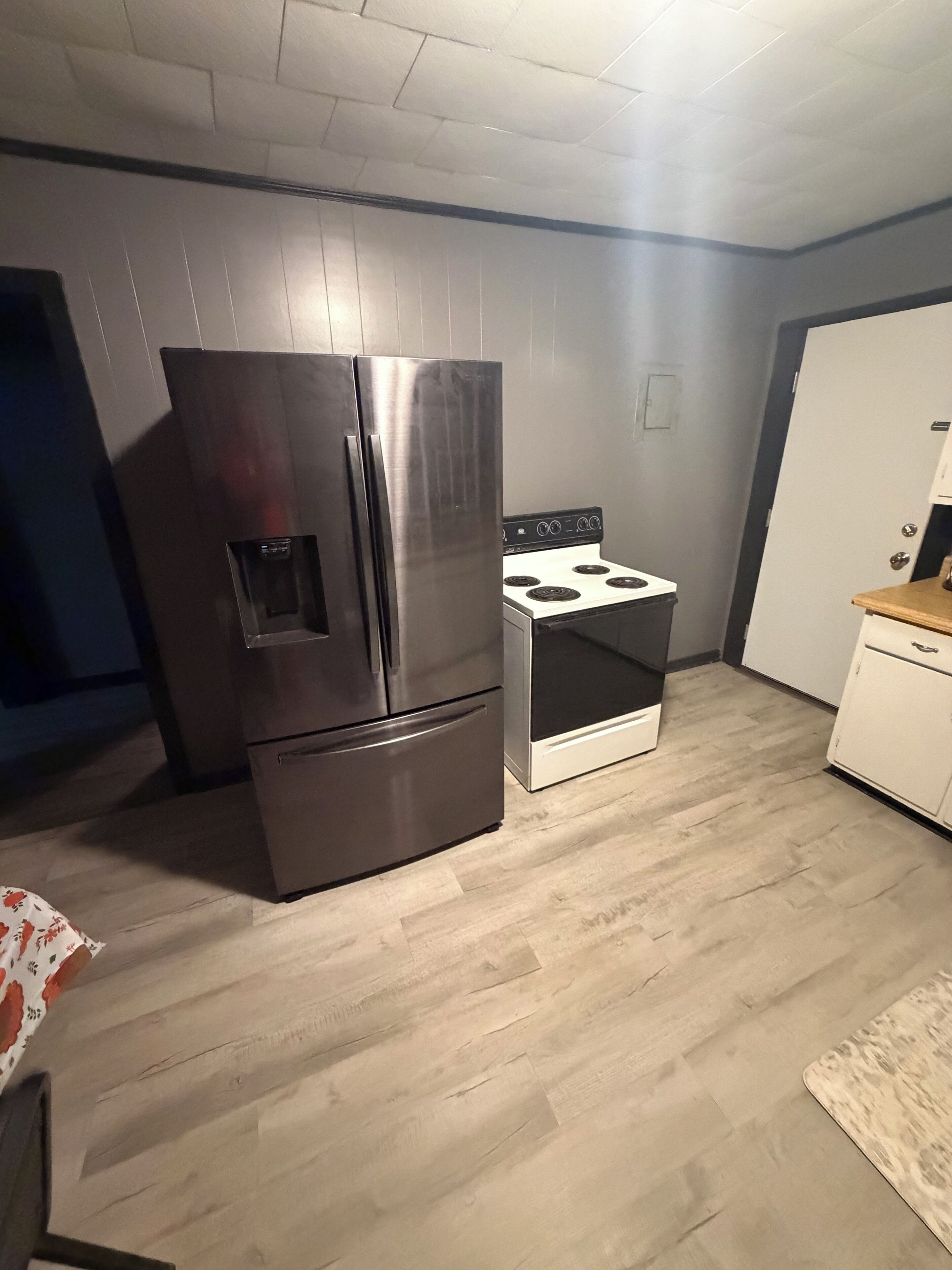Una cocina con un refrigerador de acero inoxidable, una estufa y un armario blanco.