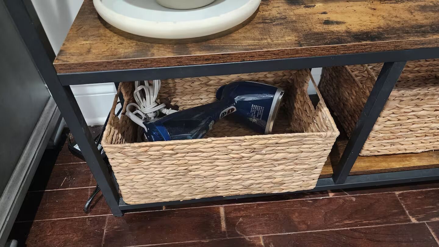 A kitchen area with a wooden countertop, a white sink, and woven baskets under the counter.