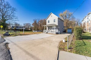 A two-story house with a front porch, a driveway, and a fenced yard.