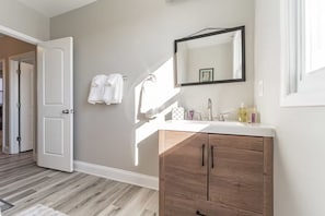 A bathroom with a wooden vanity, a large mirror, and a white sink. - 4-bedroom house in tranquil Baltimore Highlands with AC (Baltimore Highlands)