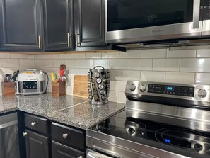 A kitchen with a stainless steel microwave, oven, and a digital clock displaying 10:43.